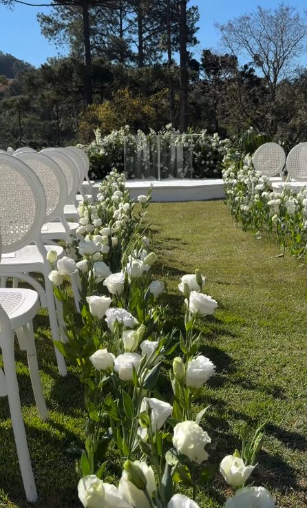 Corredor no gramado com lisianthus brancos e cadeiras de palhinha